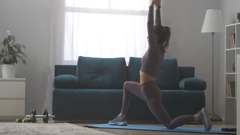 Gimnasia-Para-Estirar-En-Casa-La-Mujer-Está-Realizando-Yoga-Asana-Pose-De-Guerrero-Para-Estirar-Los-Músculos-Entrenando-Sola-En-La-Sala-De-Estar