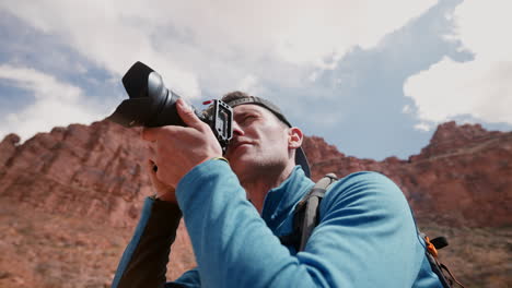 un joven fotógrafo toma una foto del paisaje del desierto entre el terreno salvaje y rígido de las montañas del suroeste de arizona - aficiones, creatividad, diversión