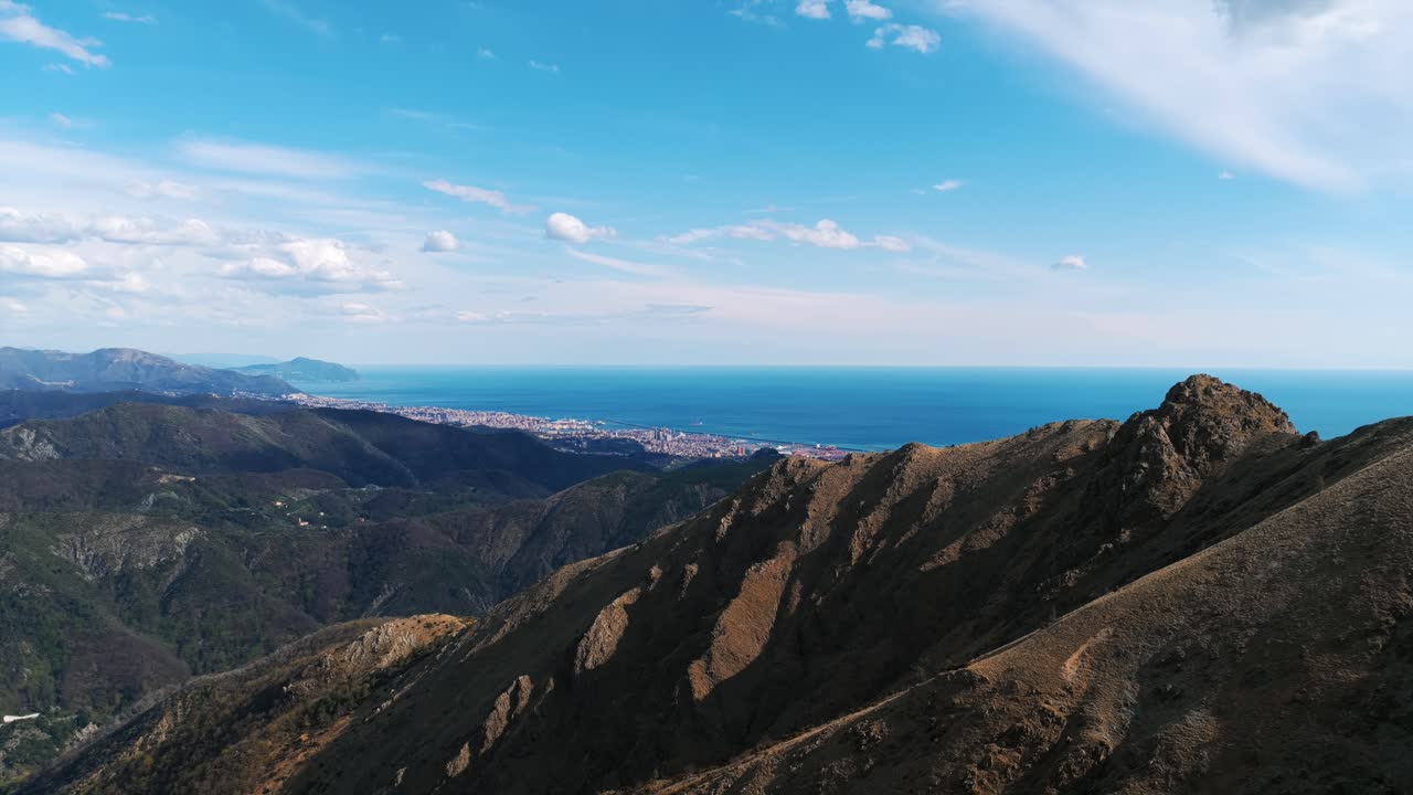View From Ligurian Apennines With Rugged Peaks In Foreground, Overlooking Coastline And Ligurian Sea In Liguria, Italy. wide aerial shot
