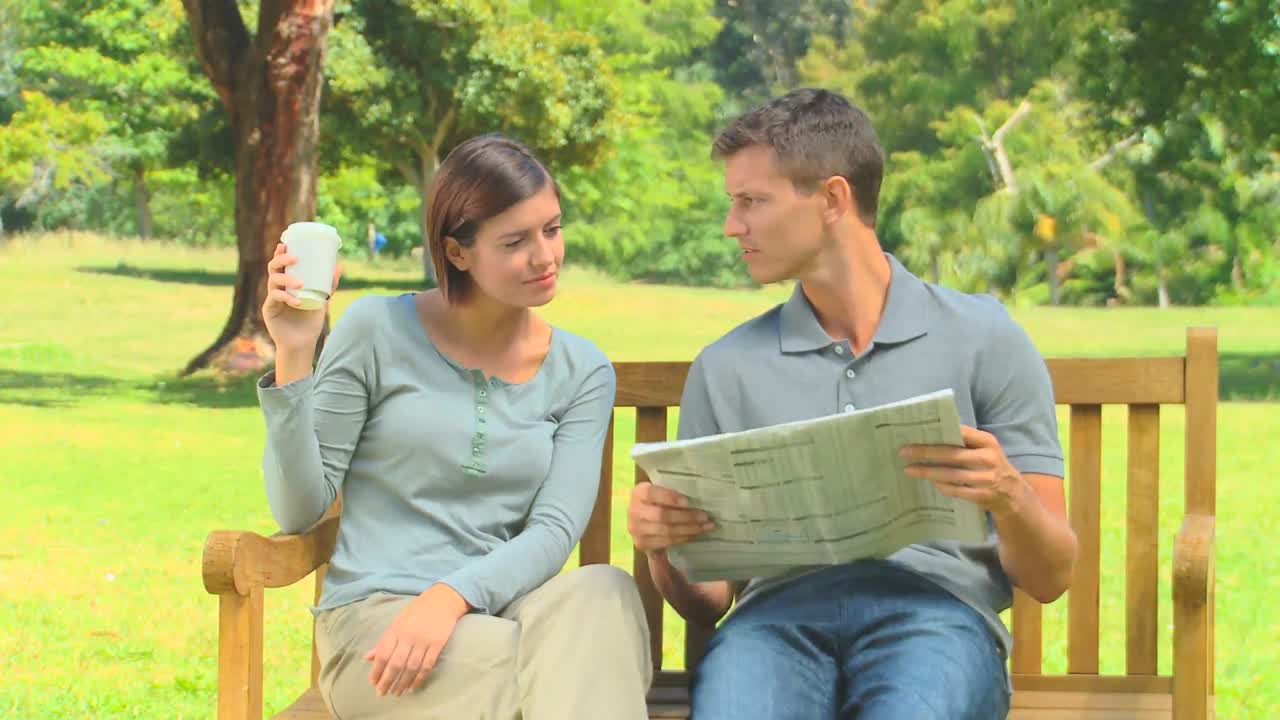 una pareja joven leyendo un periódico.