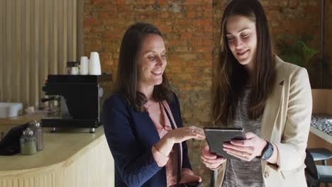 caucasian female business owner and her coworker using tablet and talking