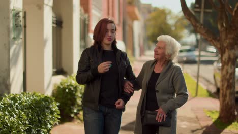 elderly woman and young woman walking and talking on a sidewalk