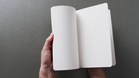 close up of hand leafing through book with copy space on gray background in slow motion