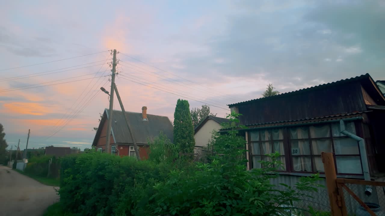 해가 지는 동안 전기 기둥과 함께  도로 근처의 외 발트 지방의 오래된 목조 집