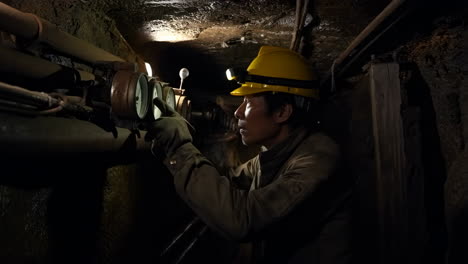 miner inspecting gauges in an underground tunnel