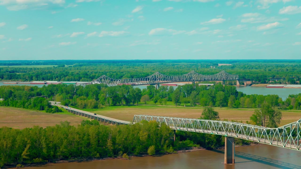 Pontes históricas de treliça de ferro atravessando um rio largo perto de Cairo, Illinois, vãos de aço estendendo-se por uma floresta de várzea verde sob um céu de verão claro. Ponte de Ferro do Rio Ohio em Cairo
