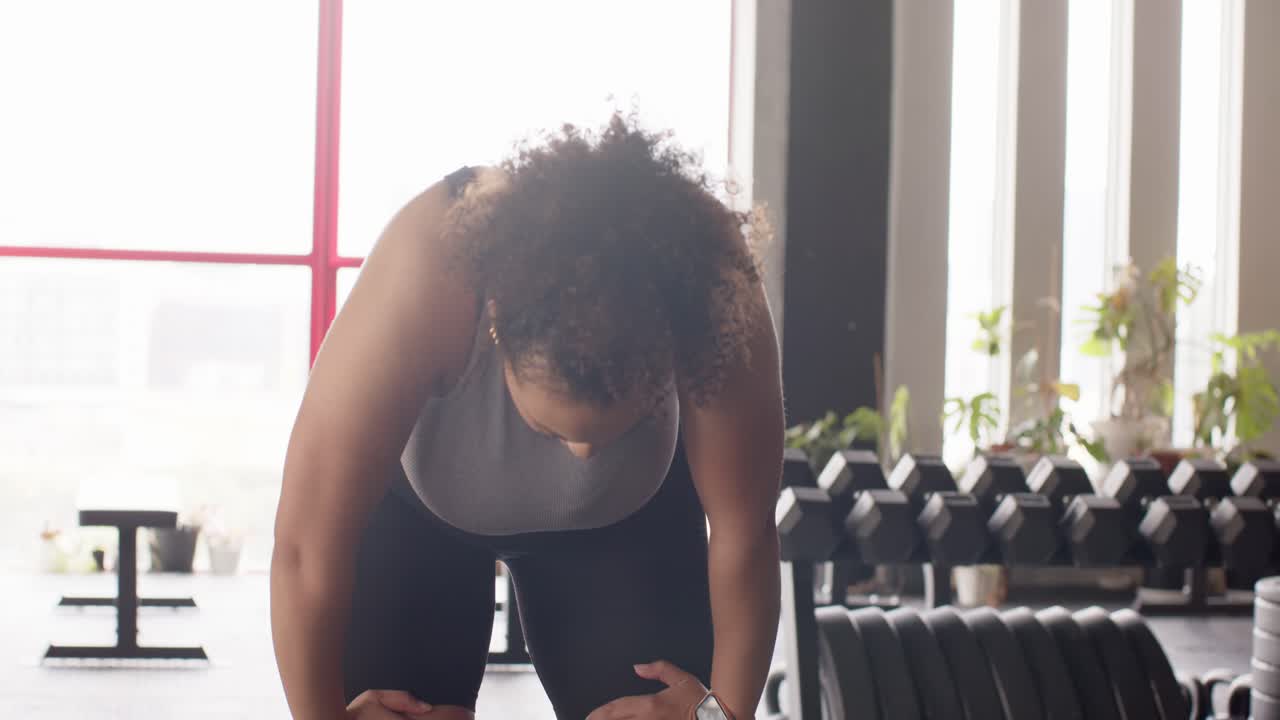 Kvinde griber fat i rebene og laver rebøvelser for at komme i form, hvorefter hun bøjer knæene og trækker vejret i fitnesscentret