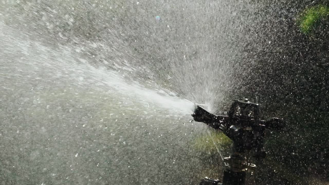 drops of water are watering plants in the yard. Automatic watering system of plants. Aerosol irrigation of garden. Slow motion