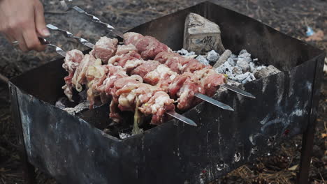 Hände-Legen-Fleischspieße-Auf-Den-Holzkohlegrill.-Fleischgrillen-Auf-Dem-Grill