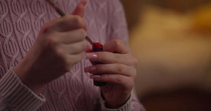 Woman Applying Lipstick with Makeup Brush on Hand
