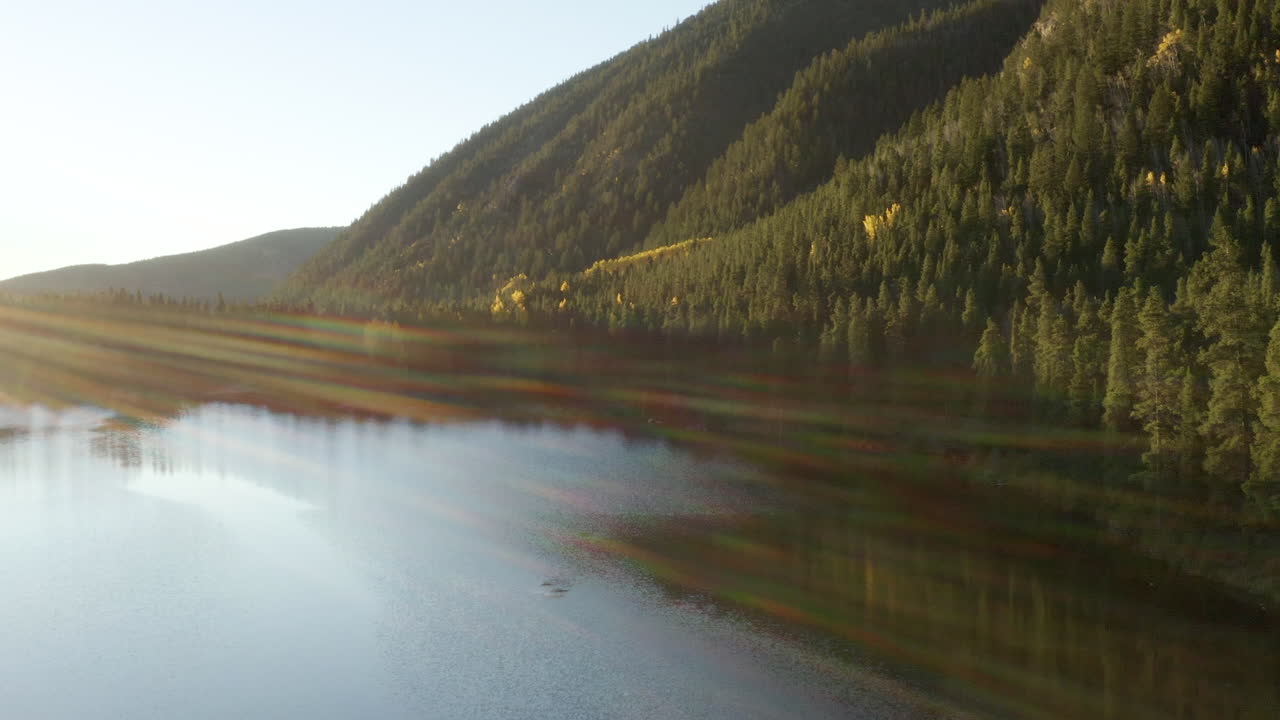 4K aerial drone footage of a sunrise over a lake in the Rocky Mountains of Colorado in the autumn or fall with changing aspen trees