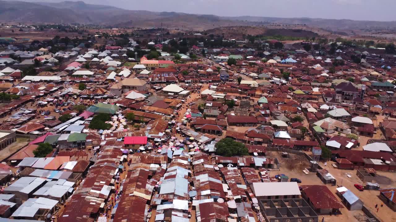 Tilt down of a large market place in the slums of Karshi, Nigeria on a sunny day