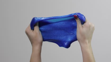 Woman-hands-playing-with-oddly-satisfying-blue-slime-gooey-substance.-Antistress