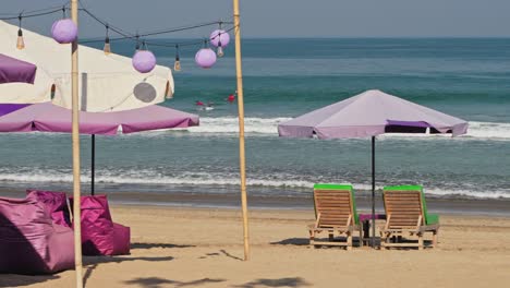 ocean waves rolling into kuta beach as people walk along the coastline