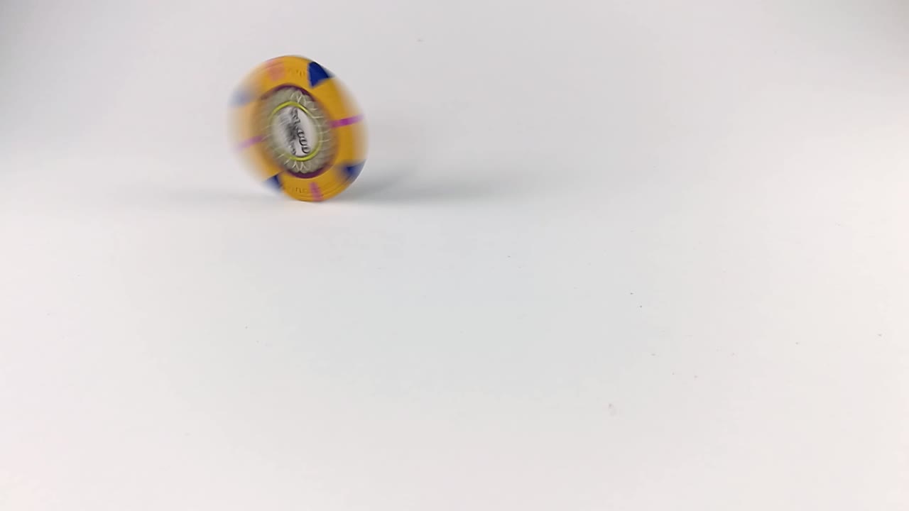 Yellow poker chip spinning on a white table, ISOLATED, STILL