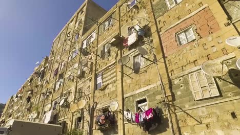 building in a dangerous ghetto with satellite dishes and laundry hanging from the balcony