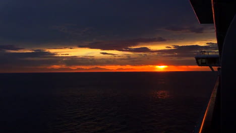 on a cruise with a amazing sunset, and you can see the land in the distance.