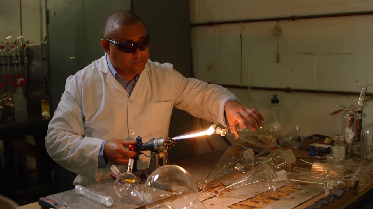 vista frontal de un trabajador masculino maduro soplando vidrio en una fábrica de vidrio 4k