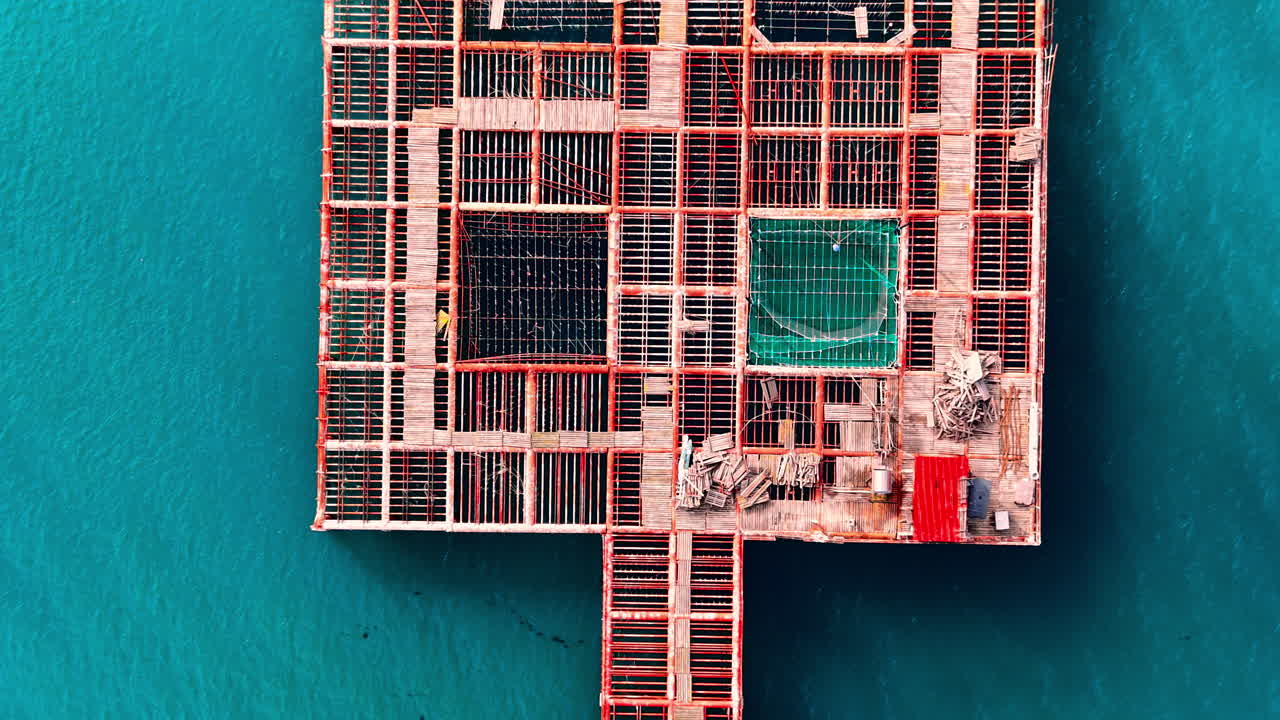 Symmetrical aerial perspective of a red grid structure for aquaculture in the open sea. Top view of industrial mussel farm structure
