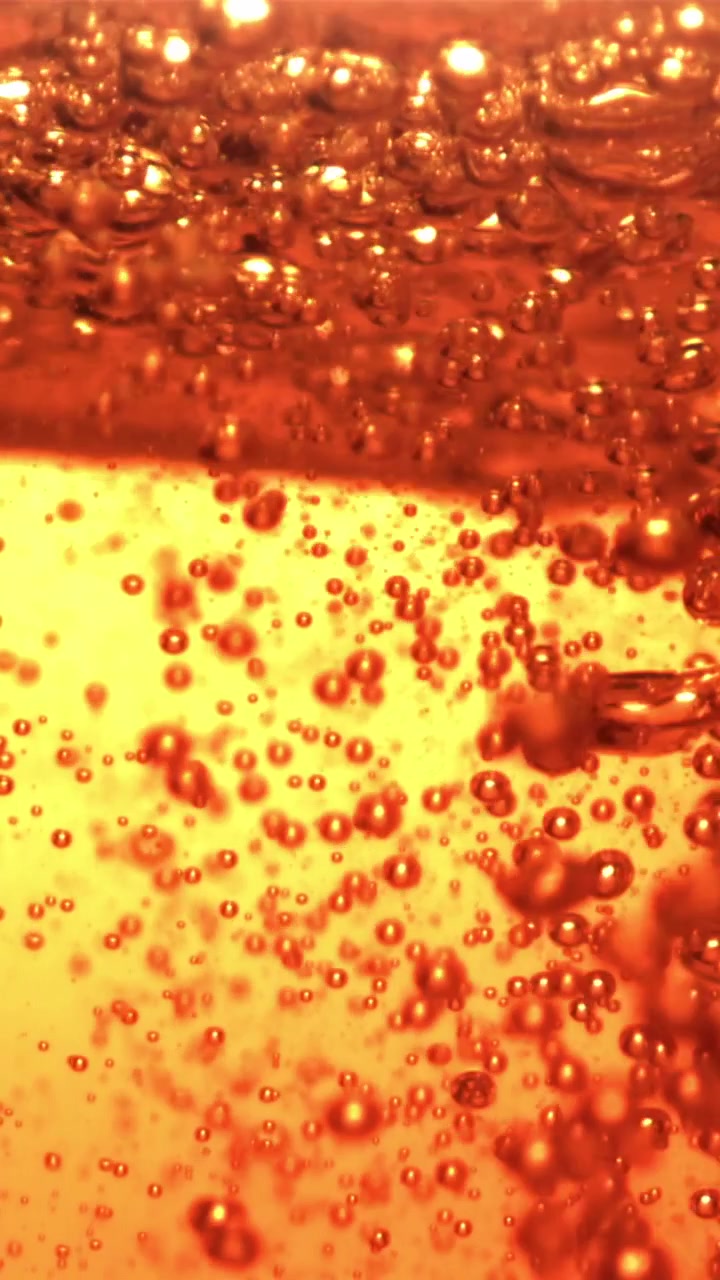 Close-up de Bolhas Vermelhas Efervescentes em Líquido Dourado