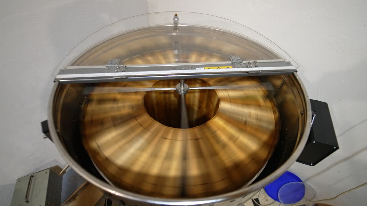 Electric device rotating frames with honey. Machine with opened lid working in the apiary. View from top.