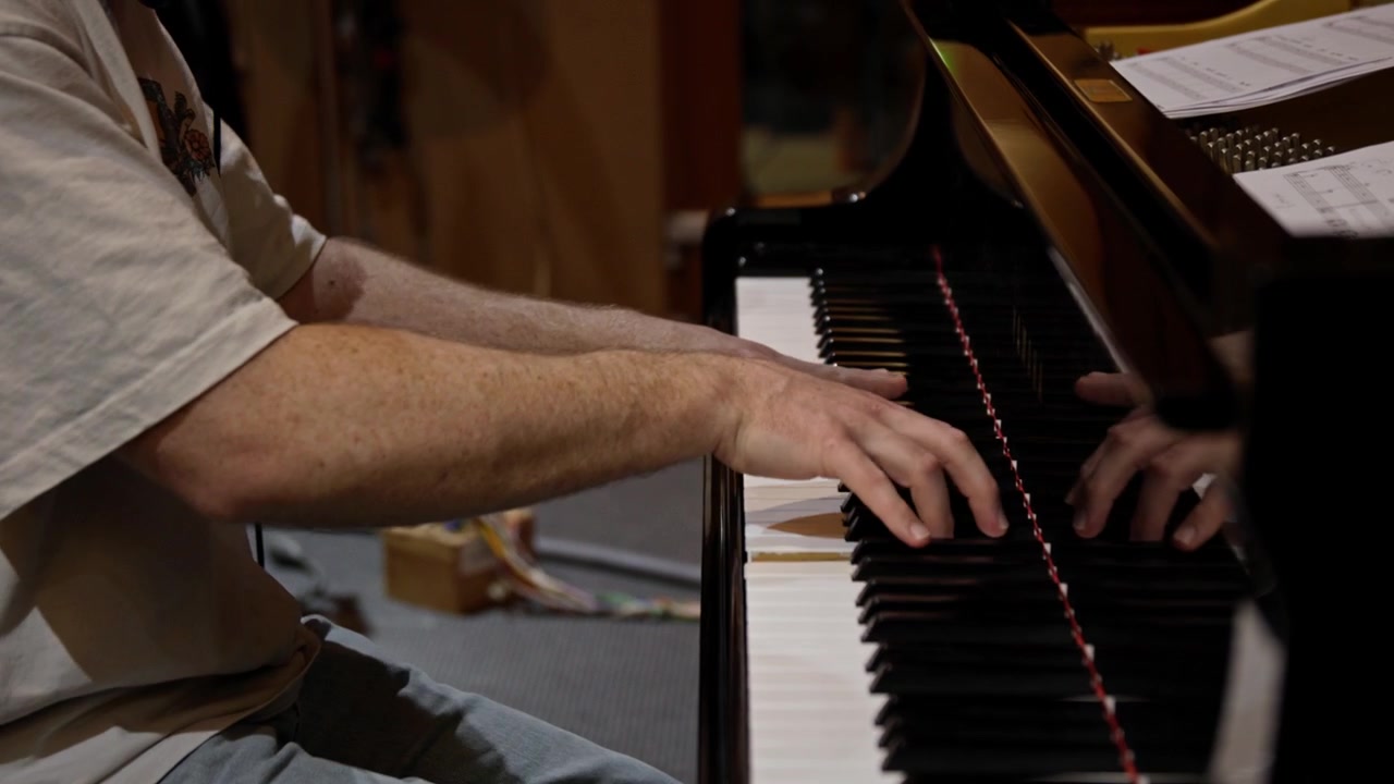 Close-up of a skilled pianist’s hands performing on a grand piano during a recording session, showcasing technique, precision, and musical expression in a studio environment.