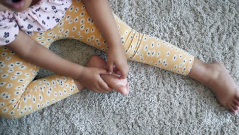 girl sitting on carpet touching her foot