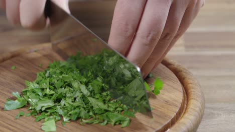 cortar perejil con un cuchillo muy afilado en una tabla de madera, un ingrediente básico de chimichurri