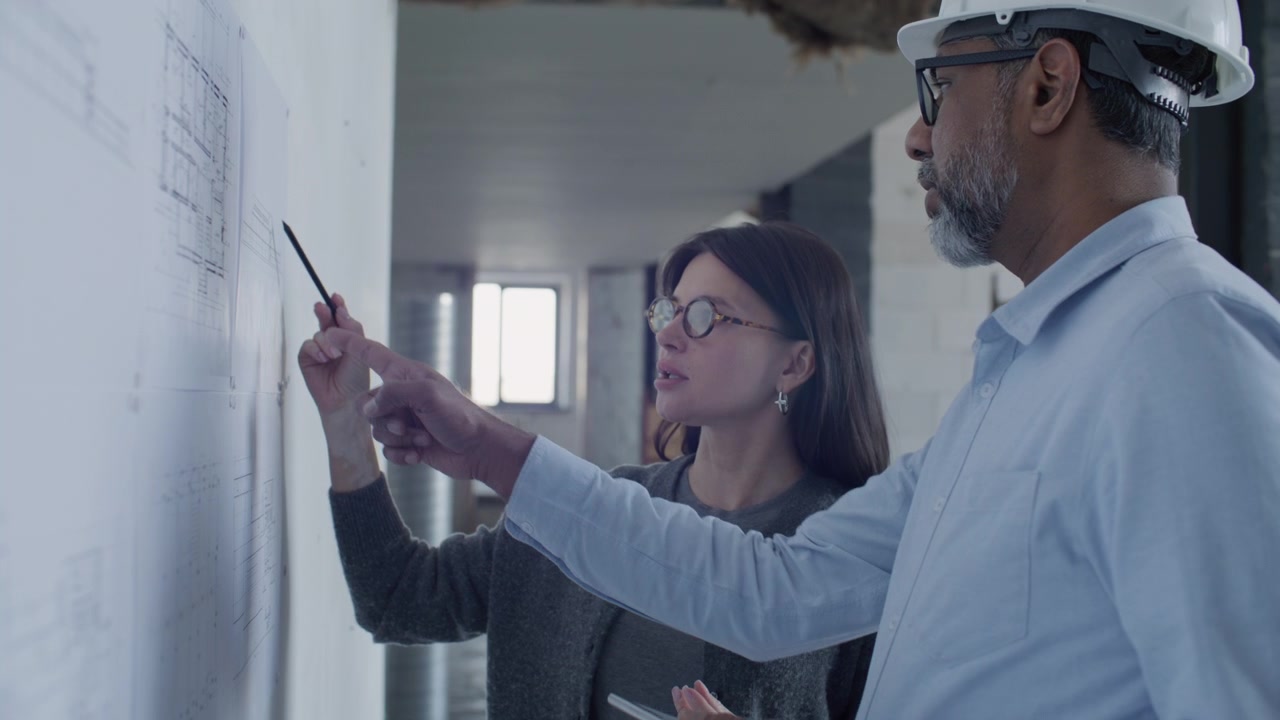 Female Architect Discussing Floor Plans with Senior Engineer on Building Site
