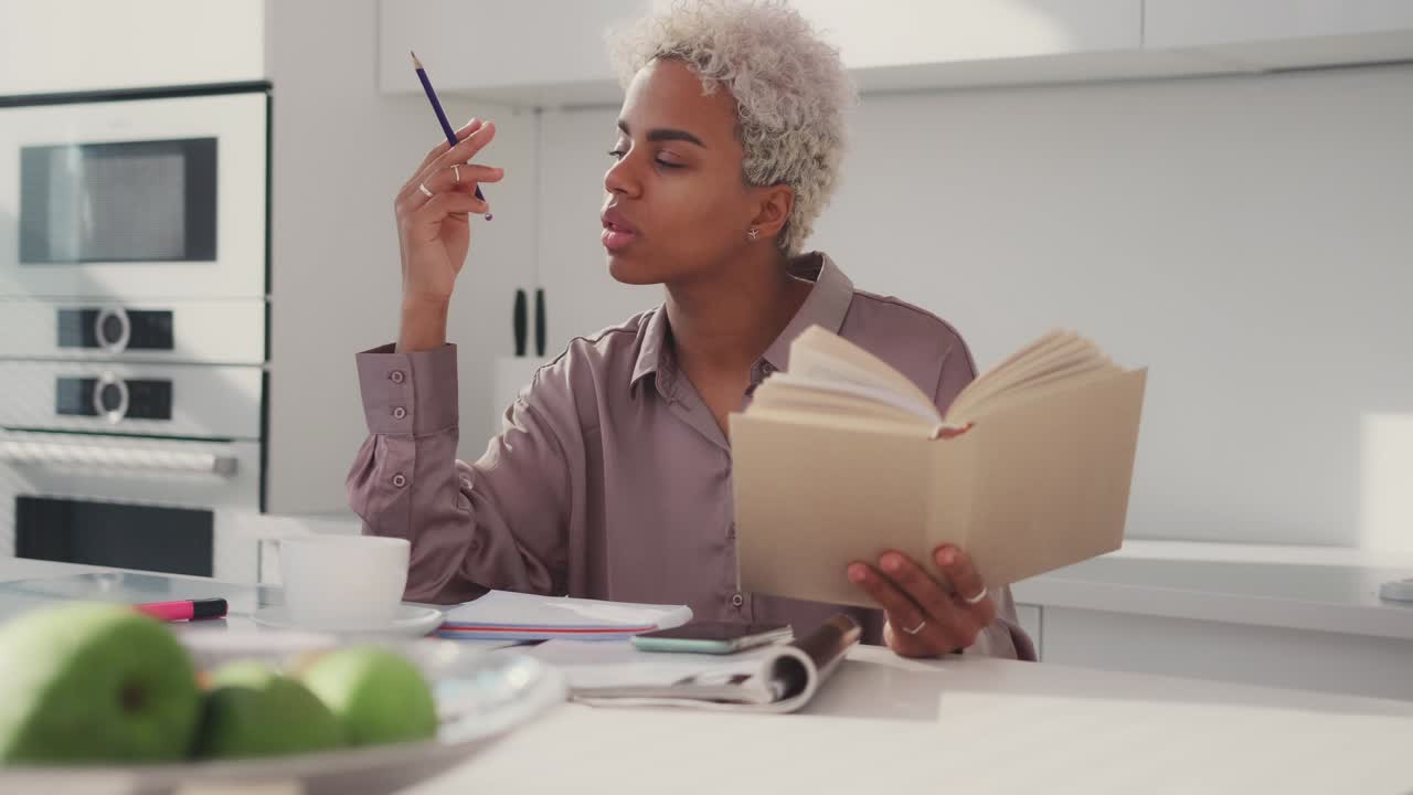 Serious focused african american woman reading textbook hold pencil take notes