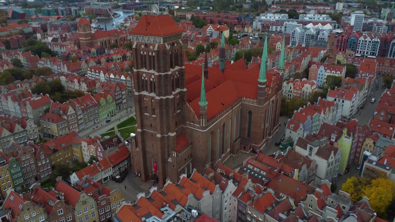 Drone view of St Mary's Basilica towering above colourful streets of Gdańsk, Poland