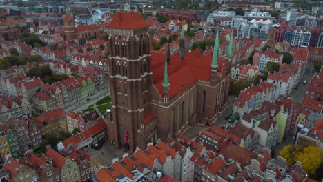 drone view of st mary's basilica towering above colourful streets of gdańsk, poland