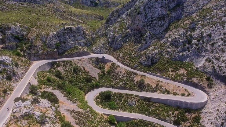 Vista aerea mentre ci si avvicina a una strada di montagna ripida, prima di passare a una vista dall'alto mentre le auto percorrono i tornanti a Maiorca