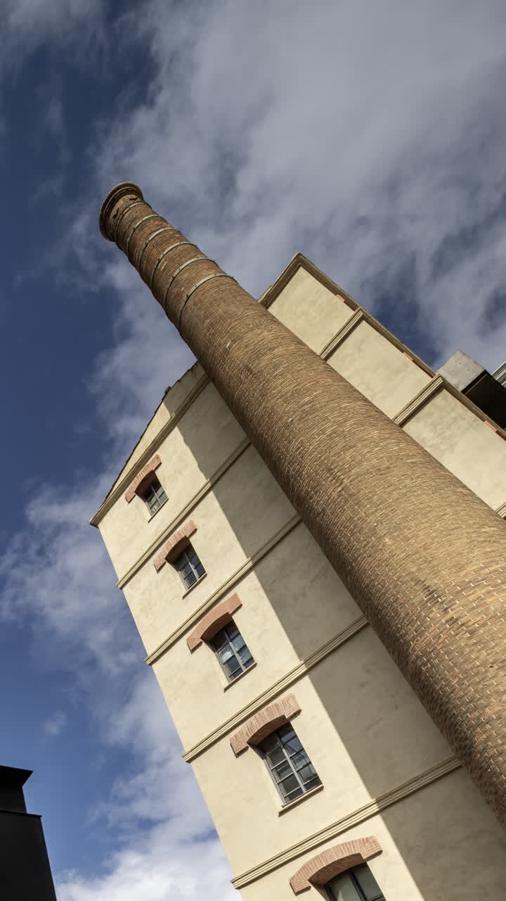 Vecchia ciminiera di fabbrica ed edifici residenziali a Barcellona in verticale