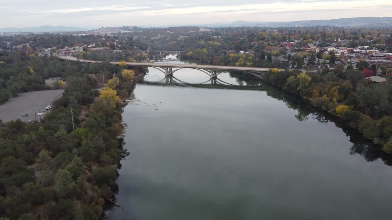 Traveling drone shot moving in on a bridge over still reflective river on a calm evening