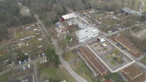 Fliegen-In-Richtung-Baustelle-In-Einer-Kleinen-Stadt,-Umgeben-Von-Wald