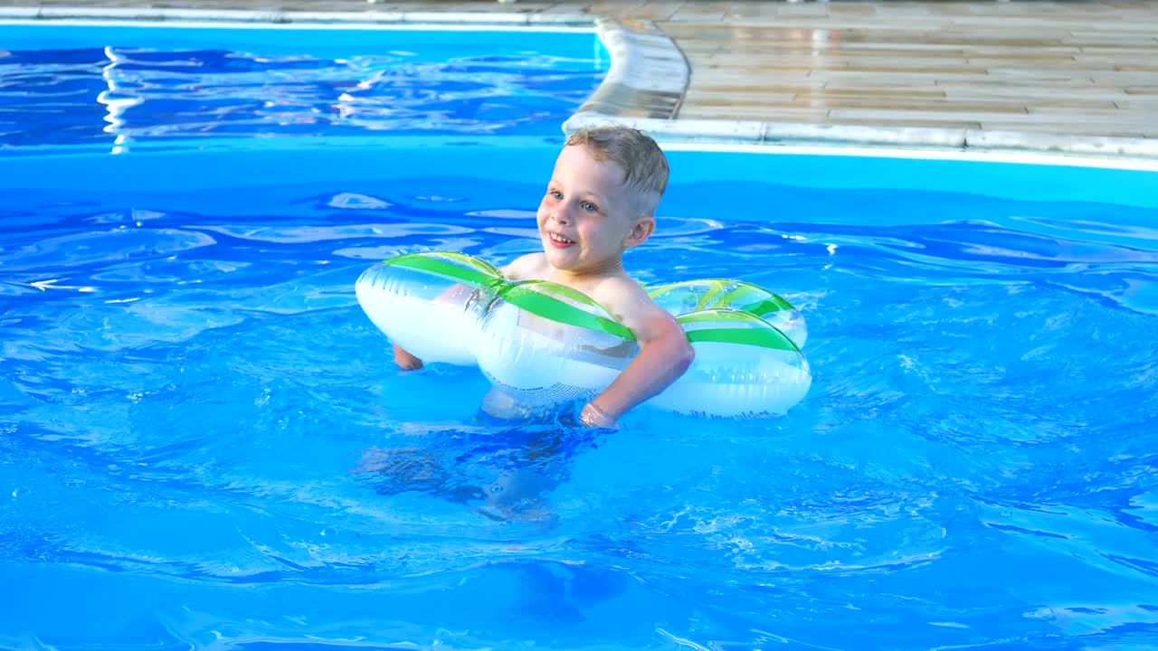 Little boy float on inflatable circle in the blue pool.
