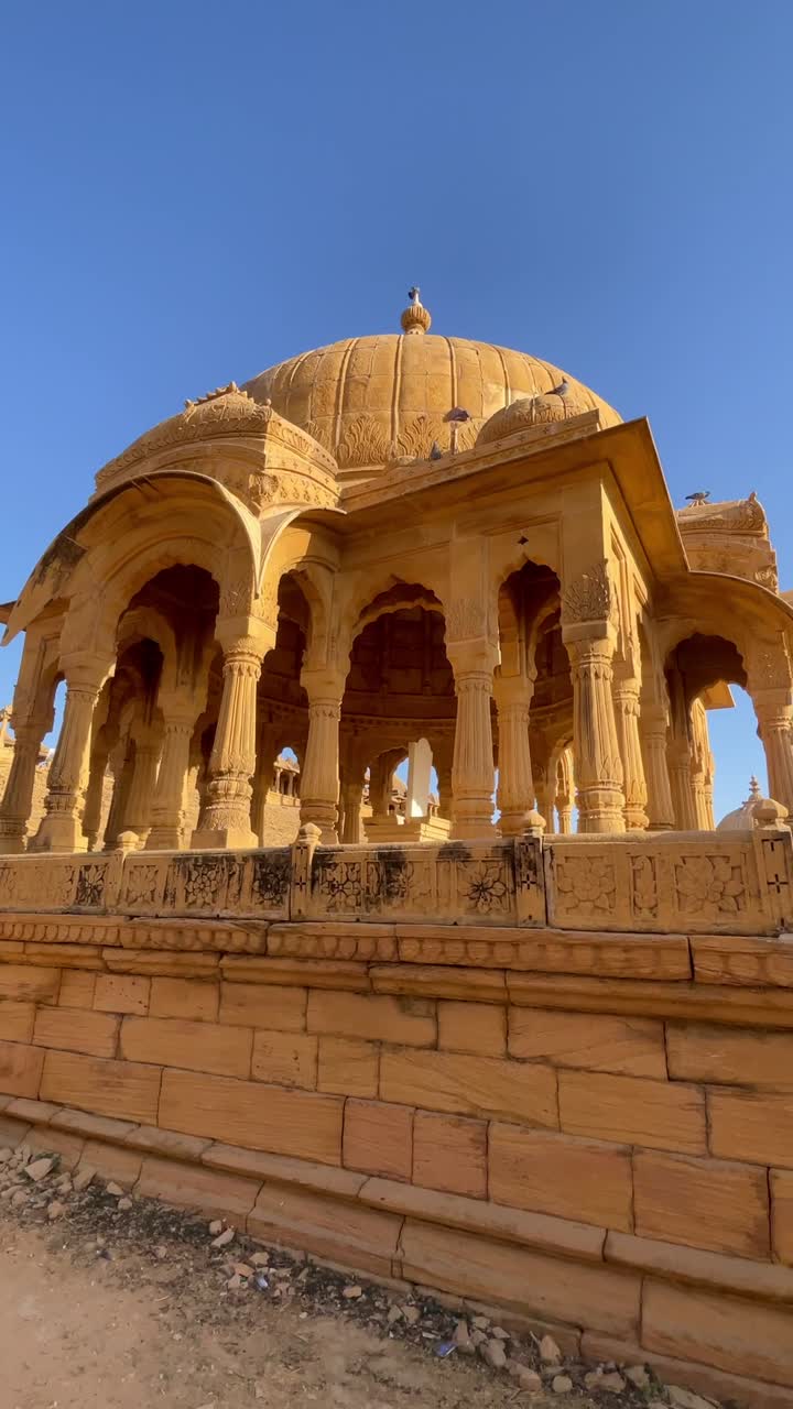 Bada Bagh in Jaisalmer is a peaceful place with beautiful old chhatris (cenotaphs) made of golden sandstone. On a sunny day, the clear blue sky Rajasthan India 4K