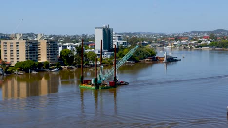 un remolcador maniobra una grúa flotante río arriba.