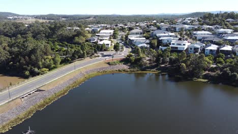 drone retrocediendo de un suburbio australiano con grandes casas familiares cerca de un lago artificial