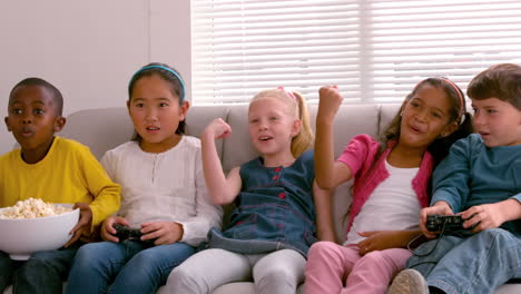 cute little friends sitting on couch together playing video games