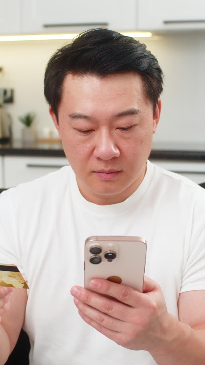 Asian man finishes payment with smartphone and credit card smiles confirmation waves approval sign