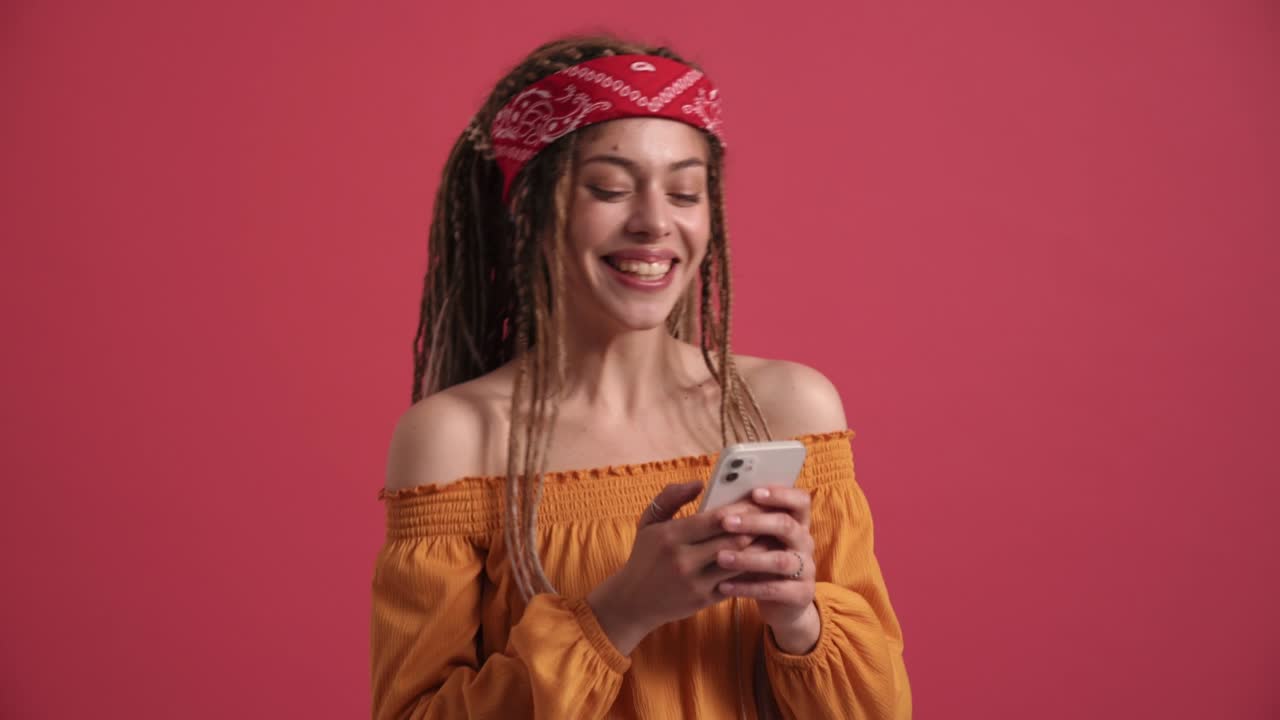 una mujer hippie riendo enviando mensajes de texto por teléfono.