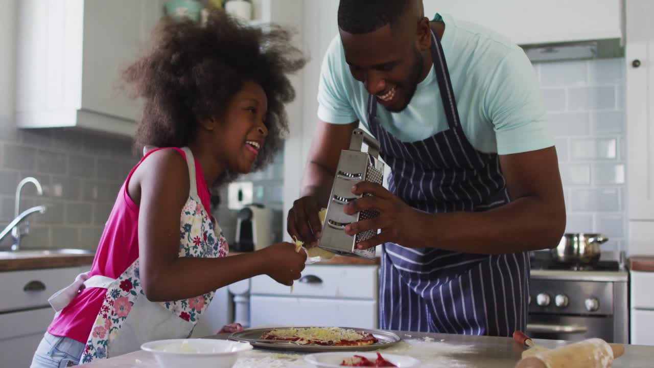 Figlia e padre afroamericani che preparano la pizza insieme in cucina.
