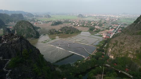 aerial flying above mua cave viewpoint revealing ninh binh city skyline, vietnam at sunset