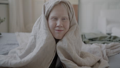 child hiding under blanket