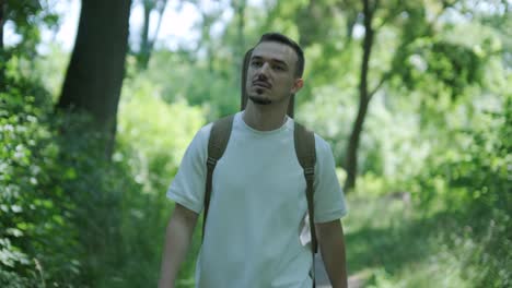 young man walking with guitar on street near forest