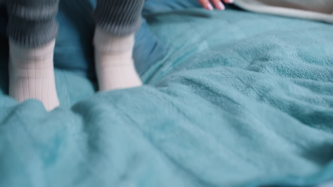 Child feet in warm socks jumping on soft bed blanket, creating cozy playful atmosphere of childhood comfort, relaxation, and carefree indoor lifestyle with focus on details of home warmth