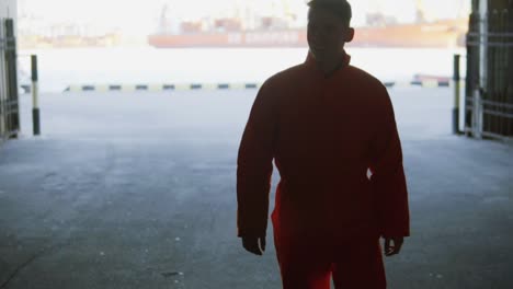 Young worker in orange uniform walking through the harbour facilities by the sea during his break. Leisure time