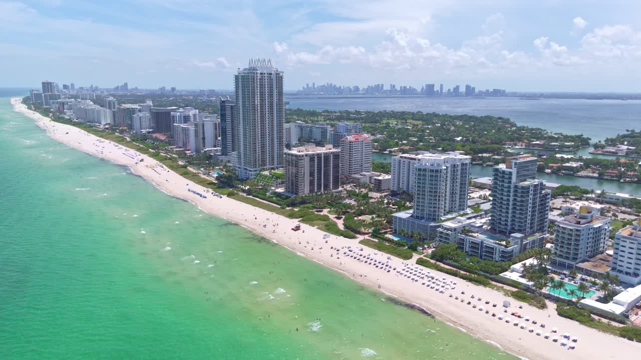 Aerial view of Miami Beach with high-rise buildings and clear water of Atlantic Ocean. Sunny day in summer. Luxury residential towers and skyline of downtown in distance, Florida. Wide shot